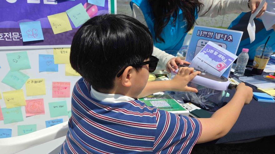 2 ‘나쁜 말 세탁소’에 참여한 어린이가 부모가 했던 상처 주는 말을 메모지에 적어 파쇄하고 있다.jpg